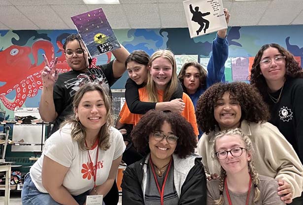 students posing for photo holding artwork